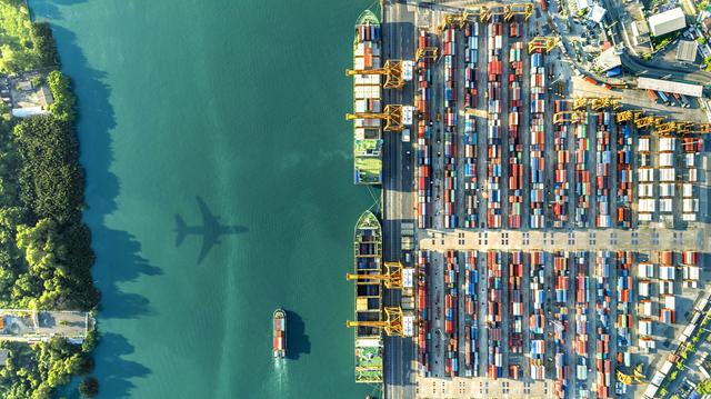 plane above sea and harbor with containers